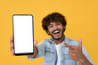 © insta_photos - Happy excited young indian man showing smartphone pointing at big mockup white blank phone template screen isolated on yellow background presenting cellphone mobile offer application ads concept.