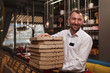 © Ihor - Cheerful waiter smiling, carrying many pizza boxes ready for delivery, copy space