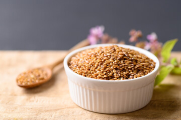 Wall Mural - Close up of golden flax seed in bowl on wooden background