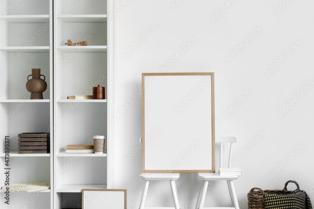 Blank poster on chairs near light wall