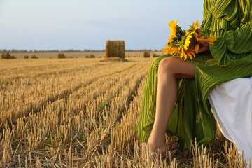 Wall Mural - Romantic young woman with sunflowers on harvested field background