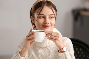 Wall Mural - Beautiful young woman drinking tasty tea in cafe