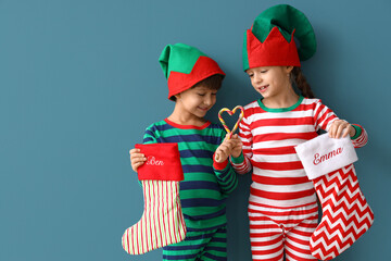 Poster - Cute little children in elves costumes and with Christmas socks on color background