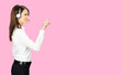 Call center service. Profile side image of customer support phone sales operator in white cloth, headset showing pointing clicking at copy space, imaginary or text, standing on rose pink background