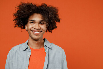 Wall Mural - Young smiling happy cheerful satisfied friendly positive black student man 50s wear blue shirt t-shirt look camera isolated on plain orange color background studio portrait. People lifestyle concept.