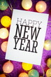 © may1985 - Happy New Year text on paper card with LED cotton balls decoration on purple background