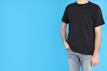 Canvas Print - Man in blank black t-shirt on blue background