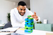 © Westend61 - Smiling male entrepreneur holding toy block at office