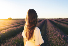 Young Woman Standing In Lavender Field During Sunset