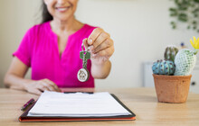 Smiling Female Real Estate Agent Giving House Key At Home Office