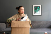 Smiling Woman Looking Away While Holding Package At Home