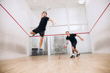 Full-length Portrait Of Two Young Sportive Boys Training Together, Playing Squash Isolated Over Sport Studio Background