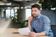 Male Professional With Paper Document Contemplating At Work Place