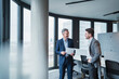 © Westend61 - Smiling business people with document in meeting at office