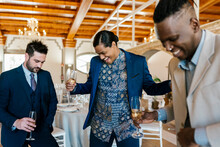 Excited Male Friends Holding Champagne Flute While Dancing At Banquet