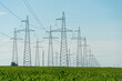 © Pokoman - power lines over an agricultural field. A high-voltage tower installed in a field with grain crops.