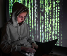 Female Computer Hacker Using Laptop While Sitting By Device Screen