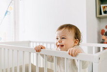 Smiling Baby Boy Looking Away In Crib At Home