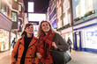 © Westend61 - Smiling female friends wearing winter coats looking away while walking together in city during night