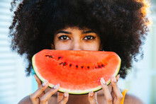 Afro Woman Covering Face With Slice Of Watermelon