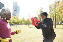 Smiling Woman Practicing Boxing With Man At Park