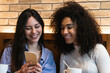 © Westend61 - Smiling female friends using smart phone at bar