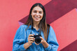 © Westend61 - Smiling female freelance worker with camera standing in front of wall