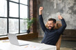 © Vadim Pastuh - Excited young businessman in smart casual wear celebrating successful deal, looking at monitor raising fists in triumph, overjoyed male entrepreneur done project, screaming yes sitting at office