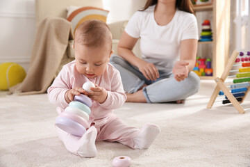 Wall Mural - Cute baby girl playing with toy pyramid and mother on floor at home