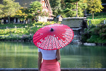 Japan, Takayama, Young Woman Holding Pink Traditional Umbrella Admiring Historical Hida Folk Village