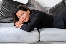 Beautiful Woman Lying On Sofa In Living Room At Home