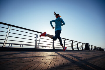 Fitness woman runner running on seaside bridge