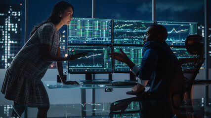 Poster - Financial Analyst Talking to Investment Banker in the Evening at Work. Chatting About Real-Time Stock Chart Data on Multi-Monitor Workstation. Businesspeople Have a Meeting in Broker Agency Office.