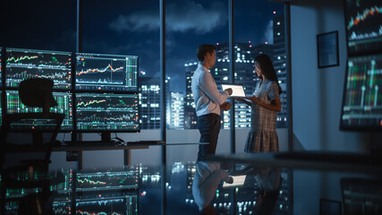 Poster - Financial Analyst Talking to Investment Banker in Late Evening at Work. Chatting About Real-Time Stock Chart Data on Tablet Computer. Businesspeople Have a Meeting in Broker Agency City Office.