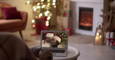 Wall Mural - Happy young couple using laptop for greeting their friends or family via video chat on Christmas eve