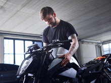 Technician Checking Motorcycle Part At Repair Shop