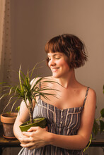 Smiling Woman With Short Hair Holding Houseplant At Home