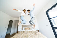 Excited Girlfriend And Boyfriend Jumping Over Bed In New Home