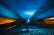 © Westend61 - Spain, Galicia, Rear view of hooded man standing under concrete bridge with bright blue light in hand