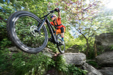 Male Athlete Riding Bike On Rock In Forest
