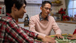 © PR Image Factory - selective focus of scheming father staring at other players while mixing mahjong pieces on table. playing tile game with family at night during chinese lunar new year
