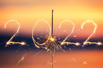 Wall Mural - 2022 written with Sparkle firework on sunset background, happy new year 2022 concept.