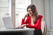 © olly - young woman uses a computer and talks on the phone at home
