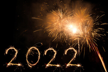 Wall Mural - New year 2022 written with bengal flame and firework in sky as a background