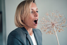 Businesswoman With Mouth Open Looking At Flower Decor In Office
