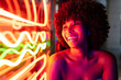 © Westend61 - Happy young woman looking at neon lights
