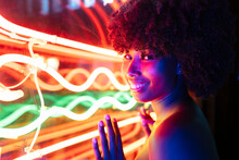 Smiling Afro Woman Touching Neon Lights