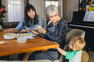 Wall Mural - Boy Looking At Family Preparing Dumplings At Home