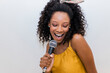 © Westend61 - Cheerful young woman singing while holding microphone against white background