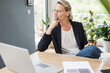 © Westend61 - Female professional with hand on chin contemplating while sitting at office
